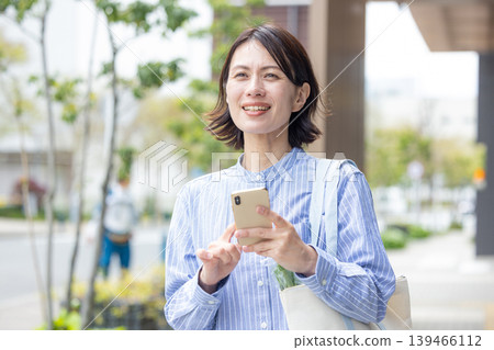 Middle women who operate smartphone outdoors 139466112