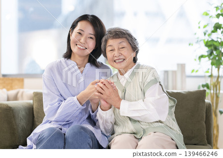 A portrait of a senior woman and a middle-aged woman, both smiling and looking at the camera, creating a mother-daughter image. 139466246