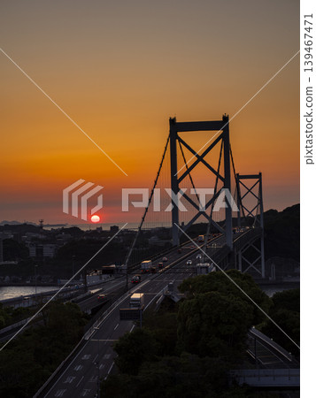 A view of the Kanmon Bridge and the setting sun from the Mekari Second Observatory. The orange-hued sea and the silhouette of the bridge are beautiful. A view of the Kanmon Bridge and the setting sun from the Mekari Second Observatory. The orange-hued sea and the silhouette of the bridge are beautiful. 139467471