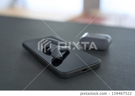Wireless earphones placed on top of a smartphone Wireless earphones placed on top of a smartphone 139467522