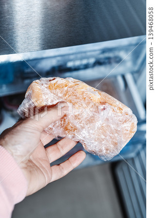 a man grips frozen chicken from the freezer a man grips frozen chicken from the freezer 139468058