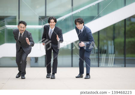 A portrait challenge and growth image of a sales team in suits making a dash (running) at the start, with three people looking directly at the camera. A portrait challenge and growth image of a sales team in suits making a dash (running) at the start, with three people looking directly at the camera. 139468223