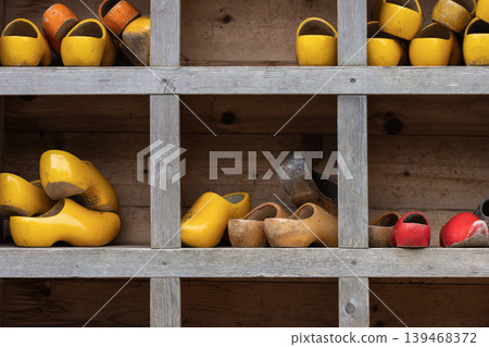 Old Colorful Wooden Clogs on Pavement Near Shelf Old Colorful Wooden Clogs on Pavement Near Shelf 139468372