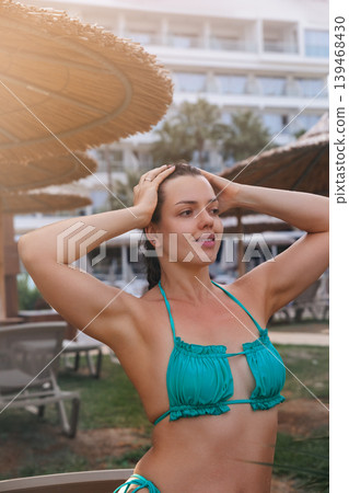 Beautiful woman touching hair with glowing radiant healthy bronzed summer skin outdoors gracefully. Beautiful female showing smooth fresh body texture during tropical resort vacation beside luxury Beautiful woman touching hair with glowing radiant healthy bronzed summer skin outdoors gracefully. Beautiful female showing smooth fresh body texture during tropical resort vacation beside luxury 139468430