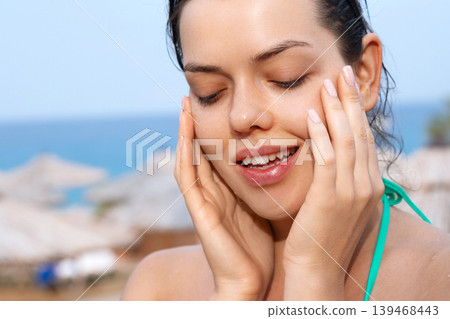 Attractive woman touching smooth facial complexion with glowing healthy radiant beauty outdoors gracefully today. Attractive female showing fresh skincare texture during tropical resort vacation 139468443