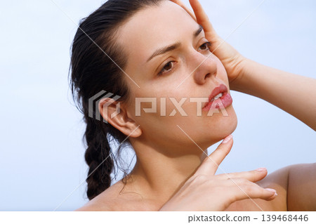 Beautiful woman touching radiant facial skin with healthy glowing smooth complexion outdoors elegantly today. Beautiful female showing fresh beauty texture during skincare routine beside tropical Beautiful woman touching radiant facial skin with healthy glowing smooth complexion outdoors elegantly today. Beautiful female showing fresh beauty texture during skincare routine beside tropical 139468446