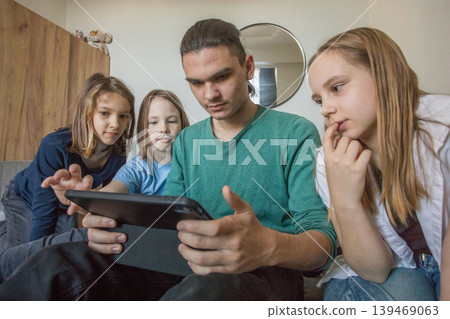 Four children sit together on a couch in a living room.  139469063