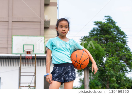 Asian student girl holding a basketball and standing on the school basketball court, Back to school and healthy lifestyle concept. 139469360