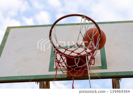Close up of a basketball scoring in the net on an outdoor court, Success and goal orientation in student sports. 139469364