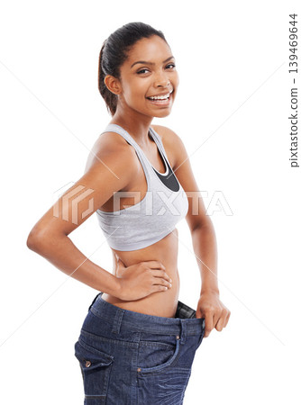 Happy woman, portrait and weight loss in diet with pants size in fitness against a white studio background. Slim young female person or model smile for thin waist, results or health and wellness Happy woman, portrait and weight loss in diet with pants size in fitness against a white studio background. Slim young female person or model smile for thin waist, results or health and wellness 139469644