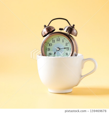 Vintage Alarm clock in white coffee cup. Vintage Alarm clock in white coffee cup. 139469678