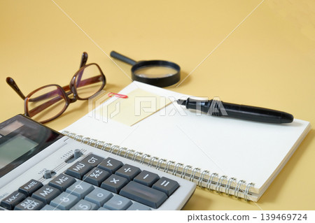 Booknote with calculator and pen on desk. Booknote with calculator and pen on desk. 139469724