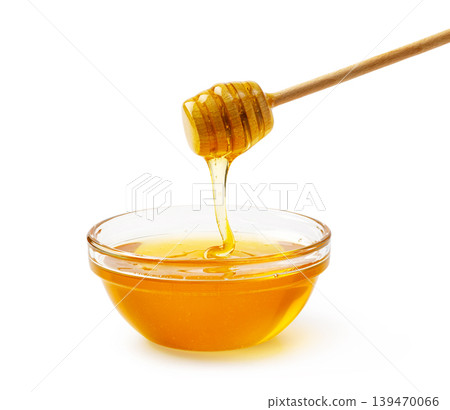 Honey dipper pouring fresh golden honey into glass bowl Honey dipper pouring fresh golden honey into glass bowl 139470066