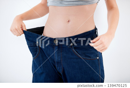 Weight, loss and woman with change in jeans, size and comparison on white background in studio. Healthy, body and person with large transformation from fitness, diet or show results in denim pants Weight, loss and woman with change in jeans, size and comparison on white background in studio. Healthy, body and person with large transformation from fitness, diet or show results in denim pants 139470125