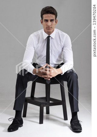 Shirt, tie and portrait of businessman with chair in studio, grey background and mock up space. Confident, man and entrepreneur sitting on stool with commitment, pride and attention in backdrop 139470284