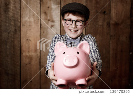 Child, piggy bank or excited in portrait by studio background, savings or finance lesson in youth. Boy, smile and face in coin banking of small change and cash learning in vintage fashion in mockup Child, piggy bank or excited in portrait by studio background, savings or finance lesson in youth. Boy, smile and face in coin banking of small change and cash learning in vintage fashion in mockup 139470295