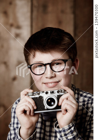 Portrait, child and vintage for camera with happiness, mockup and positive in glasses by backdrop. Boy, smile face and nerd with photography in retro clothes and eyewear for creative kids with vision Portrait, child and vintage for camera with happiness, mockup and positive in glasses by backdrop. Boy, smile face and nerd with photography in retro clothes and eyewear for creative kids with vision 139470300