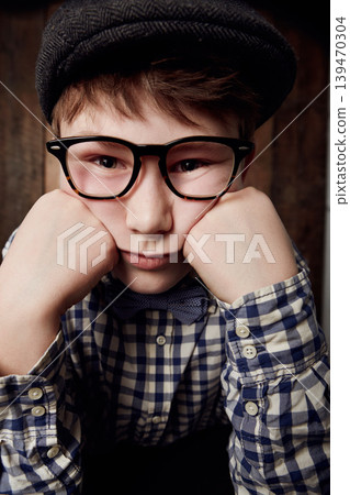 Portrait, glasses and bored kid, sad expression and thinking of depression. Tired face, nerd and young boy child in hat, geek in eyewear or exhausted with learning, serious or stress in New Zealand Portrait, glasses and bored kid, sad expression and thinking of depression. Tired face, nerd and young boy child in hat, geek in eyewear or exhausted with learning, serious or stress in New Zealand 139470304