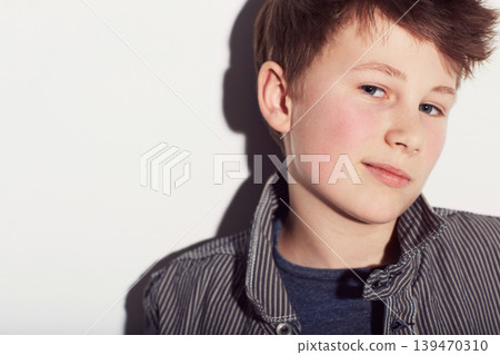 Teenager, portrait and boy with fashion in studio, white background with a smirk or smile. Cool, style and child with confidence in trendy clothes, outfit and pride in personality on backdrop 139470310