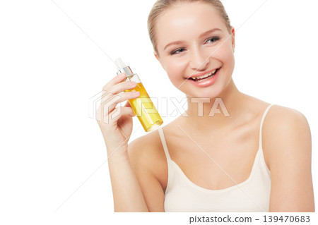 Woman, makeup and face with beauty product, smile and model for scent, cosmetics on white background. Skin, fragrance and bottle with shine, skincare or clean for glow, cosmetology or grooming 139470683