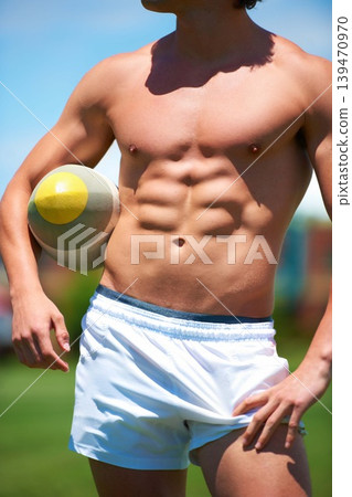 Topless, man and rugby player holding a ball closeup for training or sports practice on a field. Body, male athlete person and playing active competitive game for health and strength outdoors Topless, man and rugby player holding a ball closeup for training or sports practice on a field. Body, male athlete person and playing active competitive game for health and strength outdoors 139470970