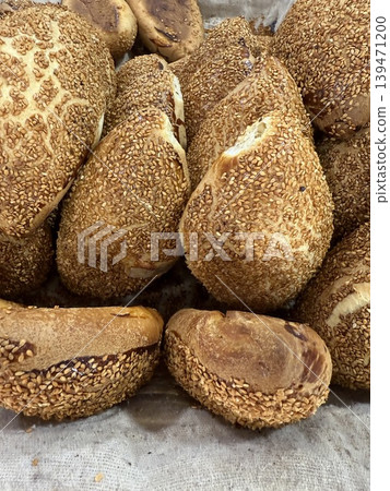 Sesame seed-covered bread rolls in a basket, showing a rustic texture and natural detail 139471200