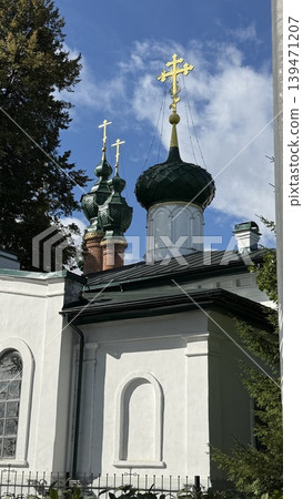 Orthodox church with green domes and golden crosses against blue sky and trees Orthodox church with green domes and golden crosses against blue sky and trees 139471207