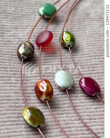 Colorful beads strung on thin wires on textured fabric background Colorful beads strung on thin wires on textured fabric background 139471212