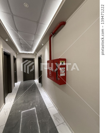 Fire extinguisher box on wall in modern building hallway, marble floor, suitable as background Fire extinguisher box on wall in modern building hallway, marble floor, suitable as background 139471222
