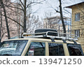 Spare tire mounted on roof rack of off-road vehicle. Travel and adventure expedition concept. Car exterior detail for wilderness journey, camping trip, and automotive maintenance. 139471250
