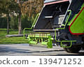 Modern green garbage truck parked on city street. Industrial vehicle for waste collection and recycling service. Professional municipal sanitization equipment for urban waste management. 139471252