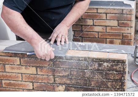 the tiler measures and puts marks to cut and lay a tile the tiler measures and puts marks to cut and lay a tile 139471572