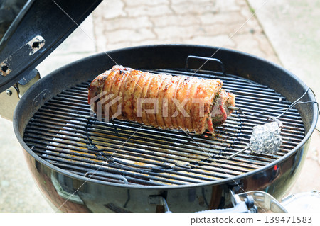 Porchetta being cooked on the barbecue and drizzled with olive oil Porchetta being cooked on the barbecue and drizzled with olive oil 139471583