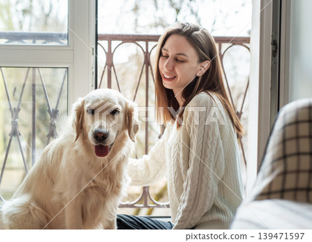 Woman and golden retriever dog sharing happy moment indoors 139471597