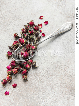 Dried rose buds and silver spoon on stone Dried rose buds and silver spoon on stone 139471613