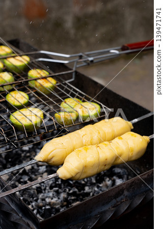 Chopped zucchini and khachapuri roasting on fire seasoned with aroma herbs and spices. Delicious fresh vegetables vegetarian grilling on barbecue smoker grid. Diet vegan bbq. Outdoor recreation Chopped zucchini and khachapuri roasting on fire seasoned with aroma herbs and spices. Delicious fresh vegetables vegetarian grilling on barbecue smoker grid. Diet vegan bbq. Outdoor recreation 139471741