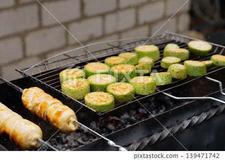 Chopped zucchini and khachapuri roasting on fire seasoned with aroma herbs and spices. Delicious fresh vegetables vegetarian grilling on barbecue smoker grid. Diet vegan bbq. Outdoor recreation Chopped zucchini and khachapuri roasting on fire seasoned with aroma herbs and spices. Delicious fresh vegetables vegetarian grilling on barbecue smoker grid. Diet vegan bbq. Outdoor recreation 139471742