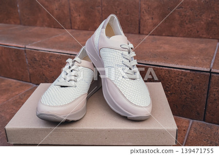 Minimalist eco-friendly white sneakers placed on recycled cardboard box, clean design for sustainable fashion concepts. New unbranded beige sneakers footwear mockups and modern product displays. For Minimalist eco-friendly white sneakers placed on recycled cardboard box, clean design for sustainable fashion concepts. New unbranded beige sneakers footwear mockups and modern product displays. For 139471755