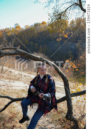 Portrait of smiling caucasian girl plays ukulele in autumnal park. Young woman plays guitar musical instrument outside in nature fall time. Audio music healing Portrait of smiling caucasian girl plays ukulele in autumnal park. Young woman plays guitar musical instrument outside in nature fall time. Audio music healing 139471824