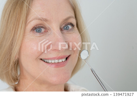 Elderly woman smiling during dental examination in clinic setting. Warmhearted senior woman showing healthy teeth during routine dental checkup in modern clinic Elderly woman smiling during dental examination in clinic setting. Warmhearted senior woman showing healthy teeth during routine dental checkup in modern clinic 139471927
