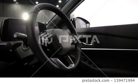 EV Car steering wheel. Modern car interior with luxury steering wheel dashboard and digital monitor controls. Steering wheel and automotive cabin. Car technology comfort and premium design in EV car. 139471994