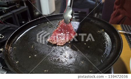 Thin beef slice sizzling on a hot cast iron griddle in a spanish restaurant for food background and menu banner design 139472036