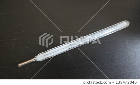 Glass mercury clinical thermometer on dark surface for medical illustration and healthcare banner design Glass mercury clinical thermometer on dark surface for medical illustration and healthcare banner design 139472040