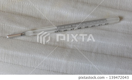 Medical mercury glass clinical thermometer on white fabric for health background and medical banner design Medical mercury glass clinical thermometer on white fabric for health background and medical banner design 139472043