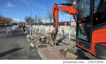 Urban road excavation with excavator breaking pavement for street repair and utility maintenance background for construction banner Urban road excavation with excavator breaking pavement for street repair and utility maintenance background for construction banner 139472046
