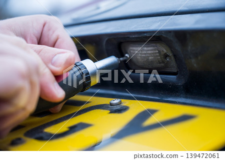 Unscrewing the screw from car light bulb, replacing the old light with a new one Unscrewing the screw from car light bulb, replacing the old light with a new one 139472061