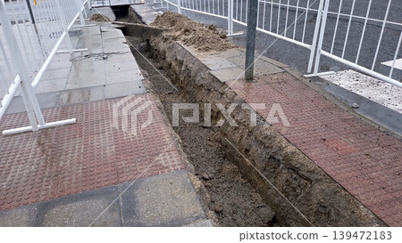 Narrow trench cut into sidewalk for underground utility pipe laying and pavement repair background for construction project signage Narrow trench cut into sidewalk for underground utility pipe laying and pavement repair background for construction project signage 139472183