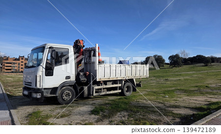 Utility flatbed truck parked on grassy verge with traffic cones and crane equipment for construction transport and maintenance site use Utility flatbed truck parked on grassy verge with traffic cones and crane equipment for construction transport and maintenance site use 139472189