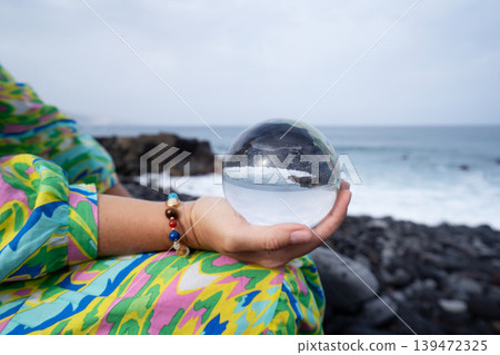woman meditating on beach shore and holding crystal ball woman meditating on beach shore and holding crystal ball 139472325
