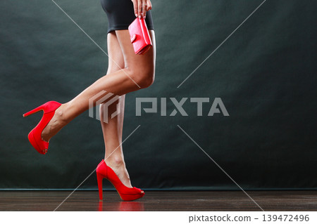 Girl in black short dress red spiked shoes holds handbag Girl in black short dress red spiked shoes holds handbag 139472496